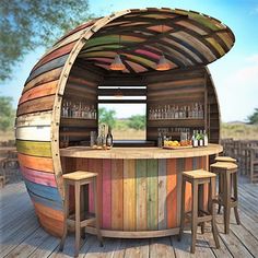 an outdoor bar made out of wooden planks and painted in rainbow colors with stools around it