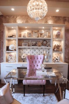 a pink chair sitting in front of a desk with a chandelier above it