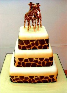 two giraffes standing on top of a three tiered cake