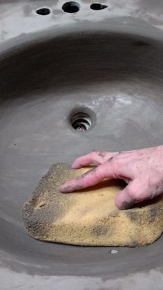 a person with their hand on a piece of cement in the middle of a sink