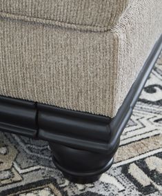 an upholstered foot rest sits on top of a carpeted area with rugs