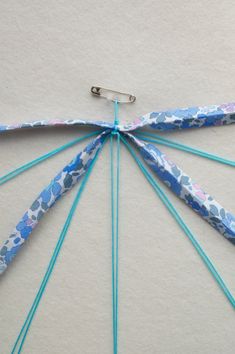 an umbrella made out of blue and white fabric with scissors on top of the string