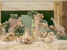 a table topped with balloons and giraffes in front of a green wall