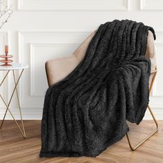 a black blanket sitting on top of a chair next to a white wall and wooden floor