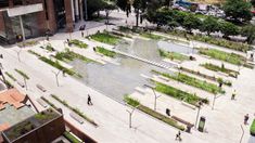 an aerial view of a city square with lots of green plants and people walking around