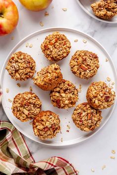 several muffins on a plate next to an apple and two bowls of granola