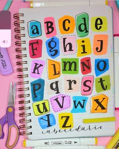 an open notebook with letters and numbers on it next to scissors, pens and markers