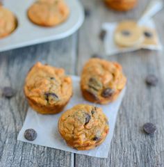 three muffins sitting on top of a wooden table next to some chocolate chips