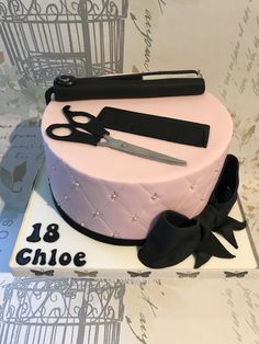 a pink cake with scissors and ribbon on top is sitting on a table next to a pair of scissors