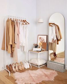 a room with clothes and shoes hanging on the wall next to a mirror that is open