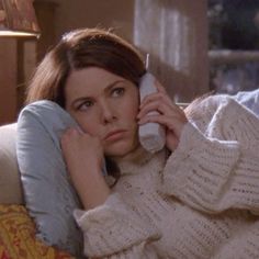 a woman laying on a couch talking on a cell phone while holding her hand up to her ear