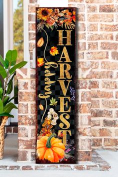 a sign that reads harvest harvest with pumpkins and sunflowers on it in front of a brick wall