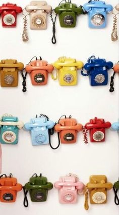 there are many telephones hanging on the wall with keys attached to them, all different colors