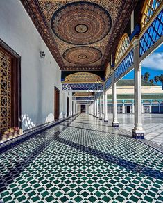 an intricately decorated hallway with blue and green tiles on the floor, in front of a white building