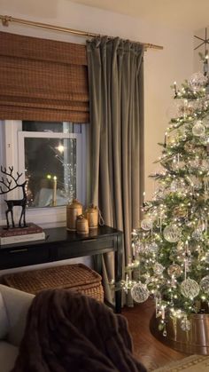 a living room with a christmas tree in the corner and a window covered by curtains