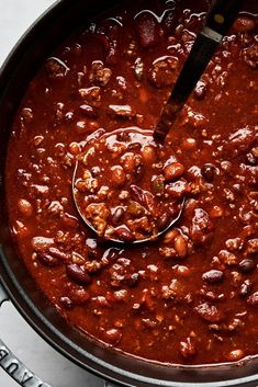 a ladle full of chili and beans in a pot