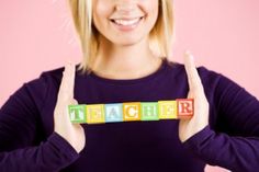 a woman holding up blocks that spell out the word teacher