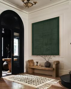 an entryway with a rug, table and vases on the floor next to it