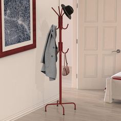 a coat rack with hats and coats hanging from it's sides next to a bed