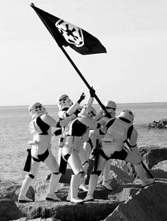 a group of stormtroopers holding a flag on top of a mountain