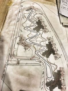 an aerial view of a race track on top of a piece of paper with construction plans in the background