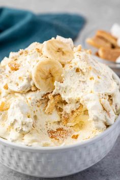 a white bowl filled with ice cream and banana slices next to crackers on the side