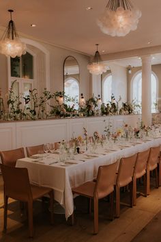 a long dining table is set up with white linens and floral centerpieces