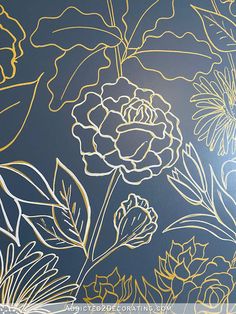 a wall with flowers painted on it in gold and blue colors, against a dark background