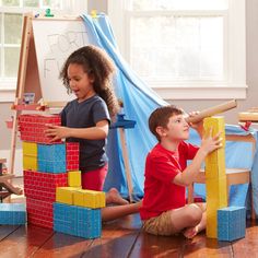 two children playing with wooden blocks on the floor