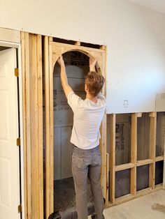 a woman standing on top of a wooden floor in front of a wall that is being built