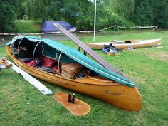 a canoe is sitting on the grass next to some paddles and kayaks,