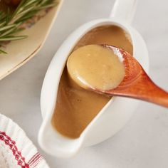 a spoon full of gravy sitting on top of a plate