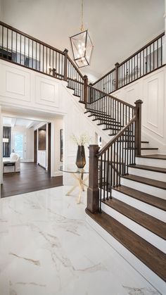 a large foyer with marble flooring and white walls, chandelier above the staircase