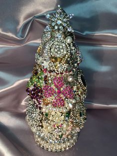 a christmas tree made out of pearls and other jeweled objects on a satin background