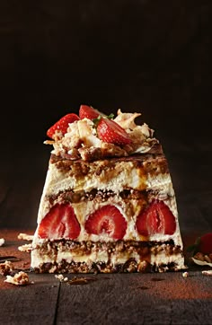 a piece of cake with strawberries and nuts on the top is sitting on a table