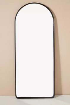 an arched mirror on a shelf against a wall with a light brown back ground and tan walls