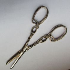 two pairs of scissors sitting next to each other on a white surface with one pair missing