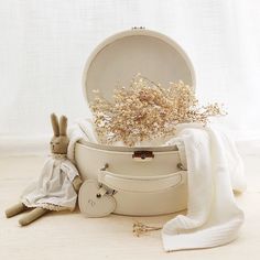 a white hat box with flowers in it next to a blanket and other items on the floor