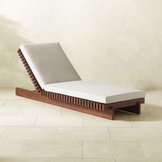 a wooden chaise lounge chair sitting on top of a tile floor next to a wall