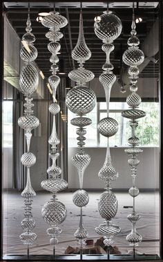 an art installation made out of glass balls and hanging from the ceiling in front of a window