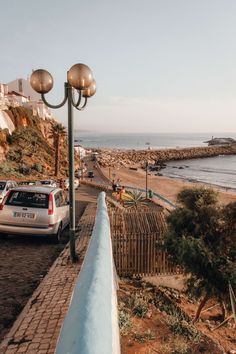 a car parked on the side of a road next to a light pole and ocean