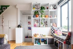 a living room filled with lots of furniture next to a window covered in bookshelves