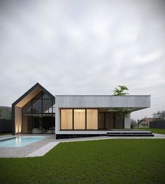 a modern house with a pool in the front yard and grass around it on a cloudy day