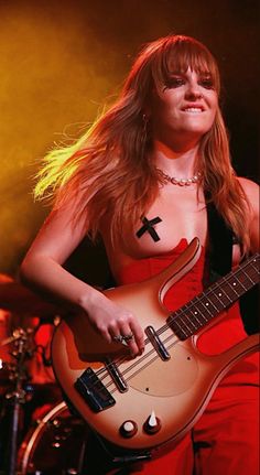 a woman in red dress playing an electric guitar