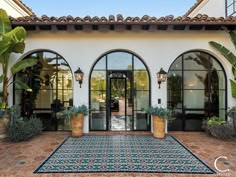 an entrance to a house with potted plants on the outside and large glass doors