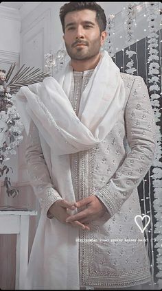 a man standing in front of a mirror wearing a white sherve and shawl