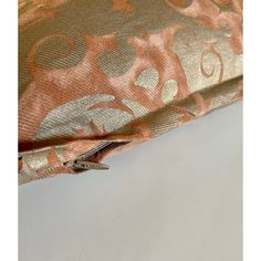 an orange and gold floral print fabric with two metal zippers on the bottom side