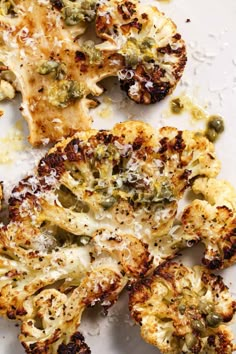 pieces of broccoli on a white surface covered in flecks and parmesan cheese