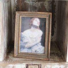 an old wooden shelf with a small painting on it's left side and a metal latch in the middle