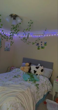 a bed room with a neatly made bed and lots of green leaves on the ceiling